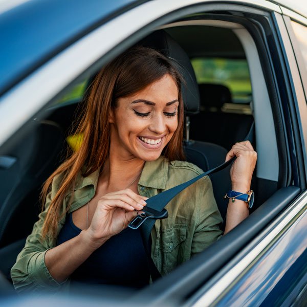 A woman buckling her seatbelt happily in the Grand Junction area