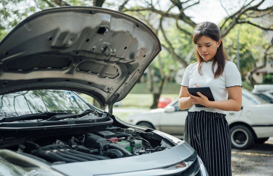 Woman inspecting a car engine for auto insurance in Grand Junction, CO