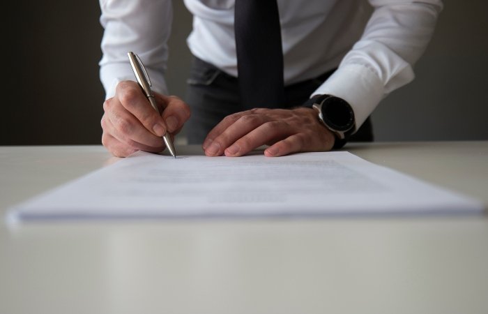 A man signing a document on a table for License Bond Services in Grand Junction, CO
