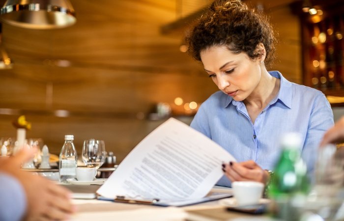 A woman at a table, focused on a document about Restaurant Insurance in Grand Junction, CO