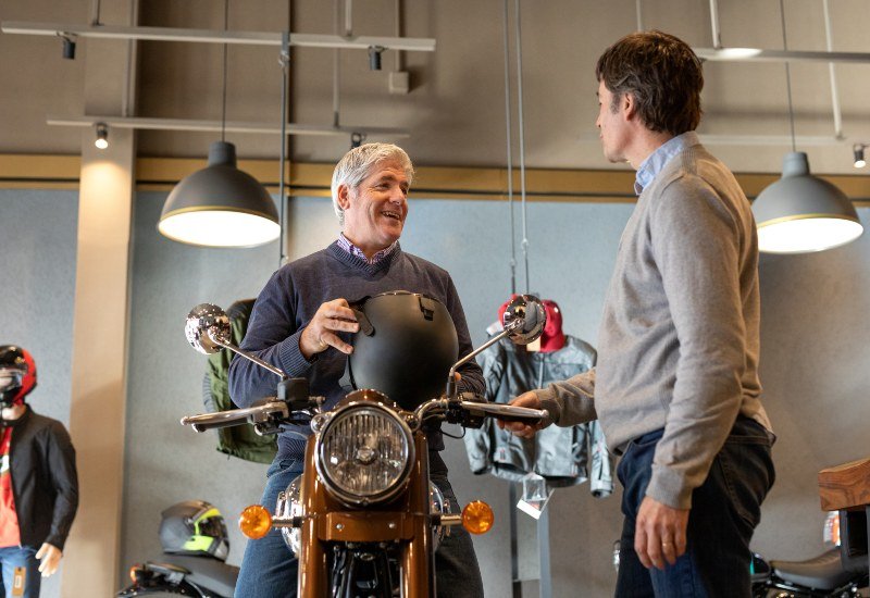 Two men are discussing motorcycle insurance in a bike shop in the Grand Junction area.